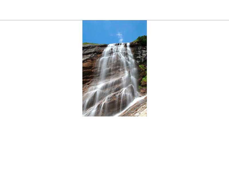 Ein beeindruckender Wasserfall fließt über Felsen in einer natürlichen Umgebung bei klarem, blauem Himmel.