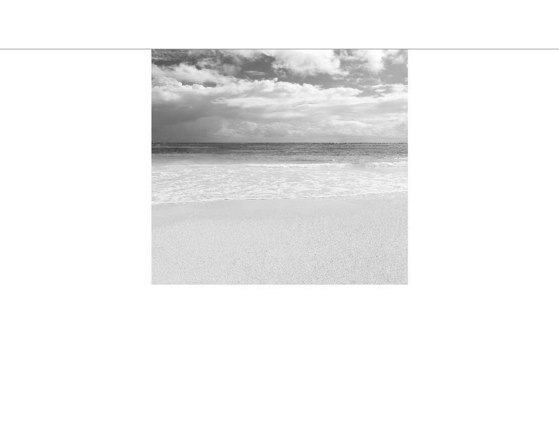 Schwarzweißbild zeigt stilles Meer mit Sandstrand und Wolken am Himmel