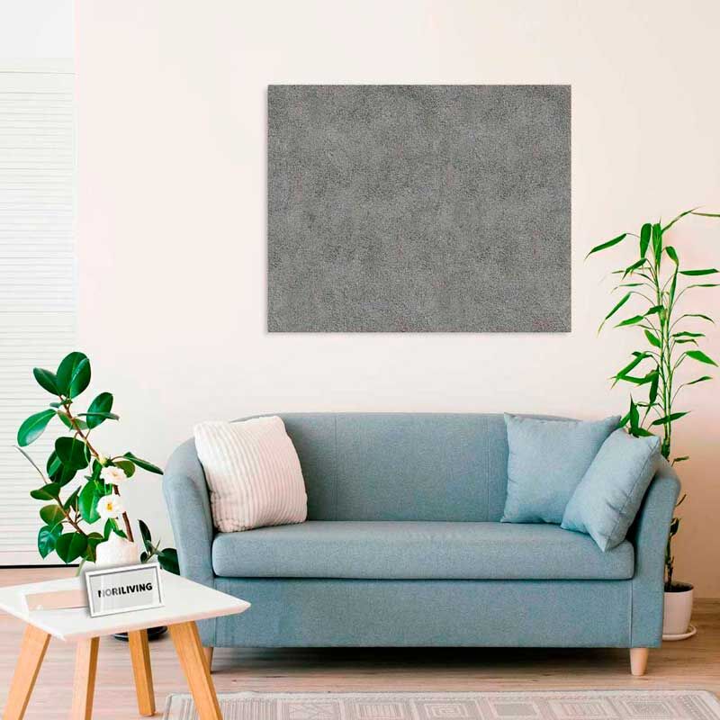 Ein gemütliches Wohnzimmer mit einer hellblauen Couch, einem rechteckigen grauen Kunstwerk an der Wand und mehreren Zimmerpflanzen.