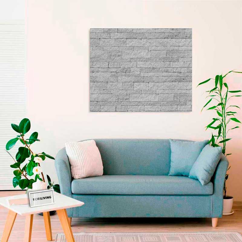 Ein stilvoll eingerichtetes Wohnzimmer mit einer blauen Couch, einem Wandbild aus grauem Mauerwerk und grünen Pflanzen.
