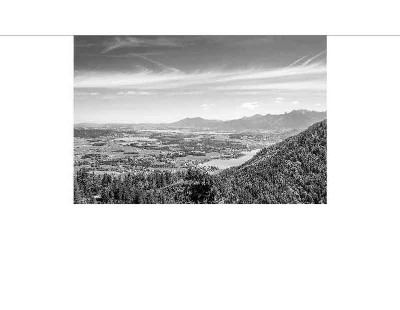 Panoramablick auf eine Landschaft mit Bergen, See und Wald in Schwarz-Weiß