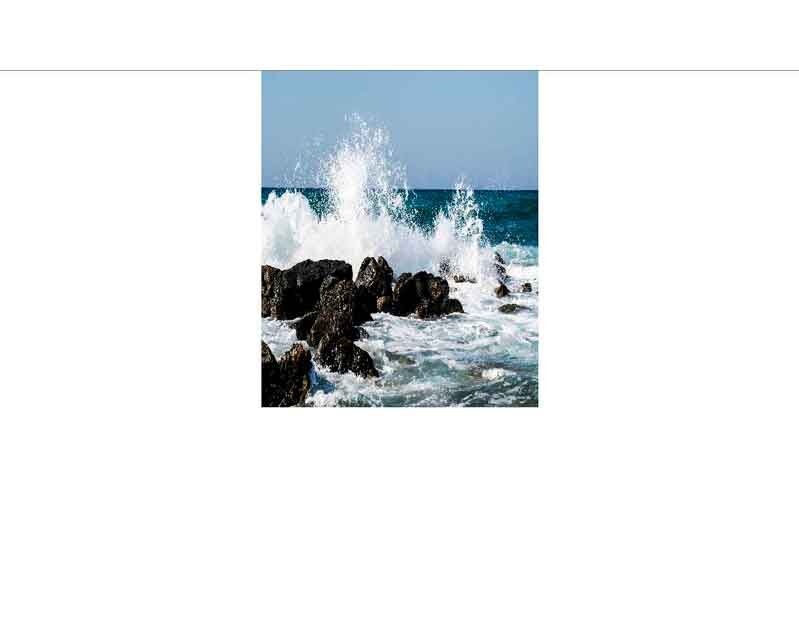 Gischtende Wellen treffen auf schwarze Felsen am Meer