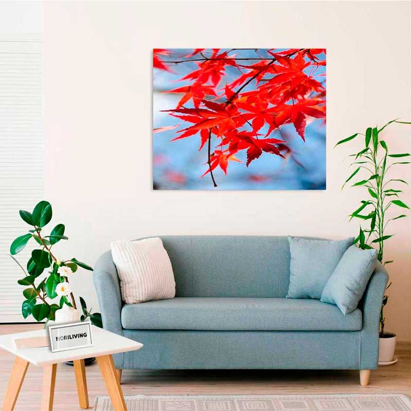 Wohnzimmer mit blauer Couch und herbstlichem Kunstbild mit roten Blättern an der Wand
