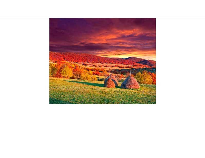 Bunte Herbstlandschaft mit Heuballen vor dramatischem Abendhimmel