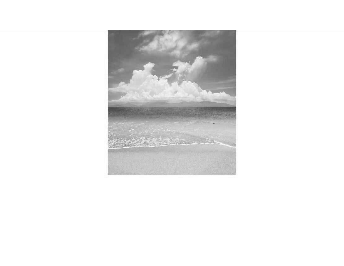 Schwarz-Weiß-Bild eines ruhigen Strandes mit sanften Wellen und bewölktem Himmel