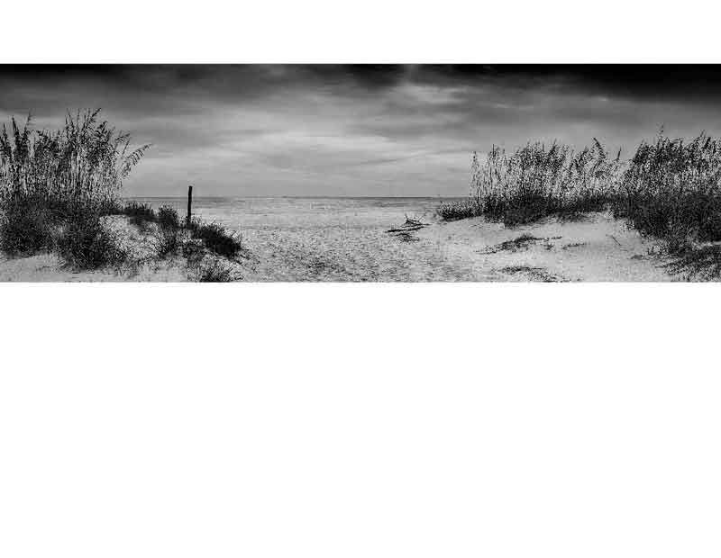 Strandpanorama in Schwarzweiß mit Dünen und wolkigem Himmel