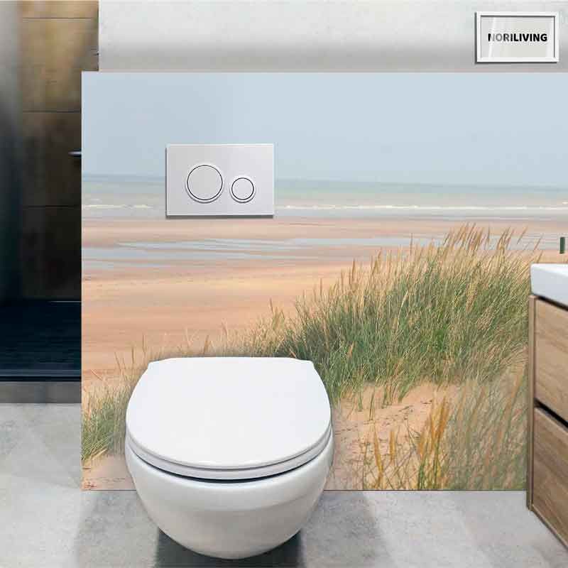 Moderne Toilette vor einer Wand mit Strandmotiv und Gräsern verziert.