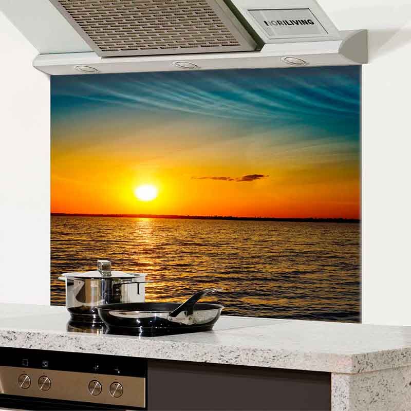Moderne Küchenrückwand zeigt Sonnenuntergang über dem Meer hinter Herd und Pfannen