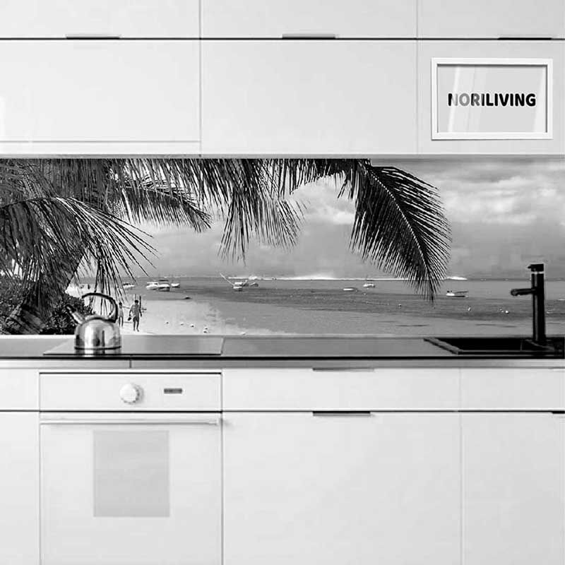 Moderne weiße Küche mit schwarzer Arbeitsplatte und einem Strandmotiv auf der Küchenrückwand