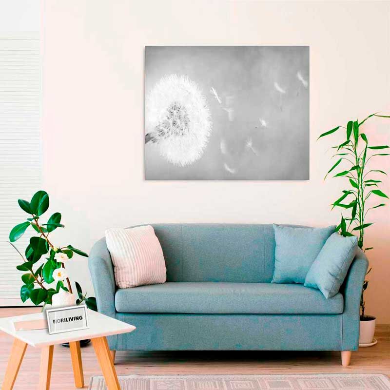 Ein gemütliches Wohnzimmer mit einem blauen Sofa, dekorativen Kissen und einer Pflanze. An der Wand hängt ein stilisiertes Bild eines Löwenzahns, das eine harmonische Atmosphäre schafft.