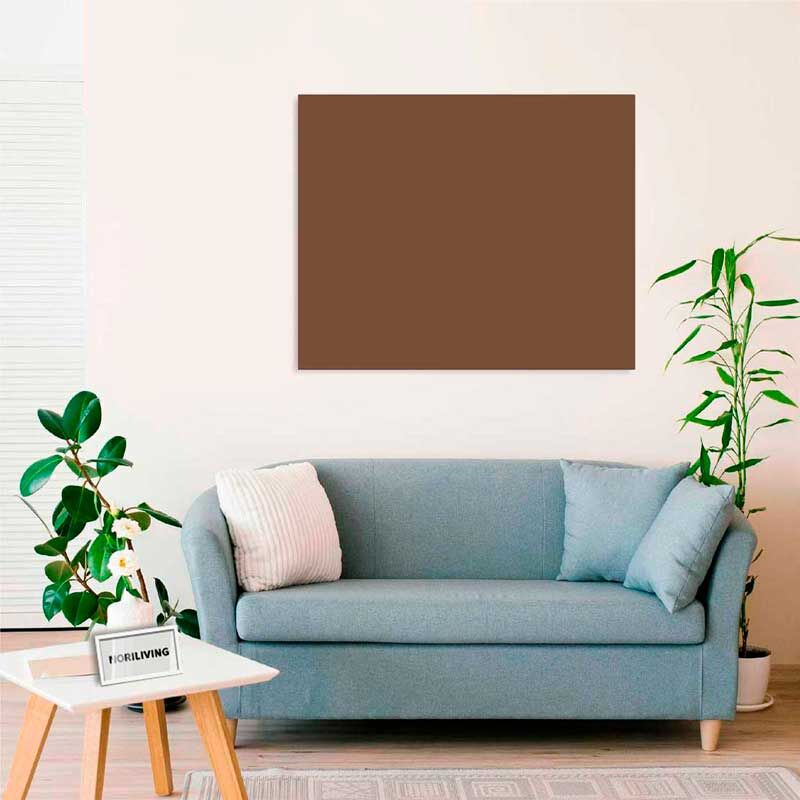 Ein modernes Wohnzimmer mit einem grauen Sofa, Zierkissen und umgeben von Zimmerpflanzen. Ein rechteckiges, leeres braunes Bild hängt an der Wand.