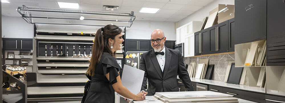 Eine Frau und ein Mann im Anzug diskutieren in einem stilvollen Küchenstudio über verschiedene Designoptionen.