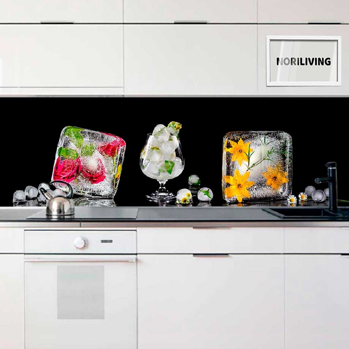 Weiße Küche mit schwarzen Akzenten, dekorativen Eisblöcken, Blüten und einem Glaskelch auf der Arbeitsfläche