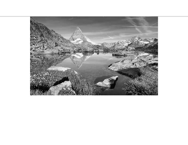 Die spiegelnde Oberfläche eines Sees zeigt eine atemberaubende Schwarzweiß-Ansicht des Matterhorns im Hintergrund.
