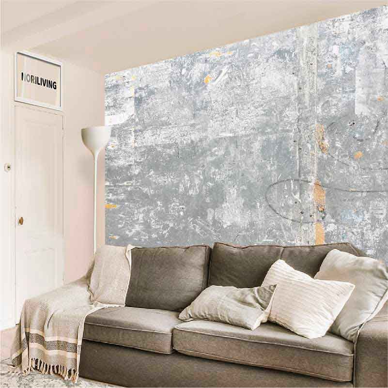 Ein Wohnzimmer mit einem grauen Sofa, dekorativen Kissen und einer Wand in Betonoptik. Ein Stehlampe daneben ergänzt das moderne Design.