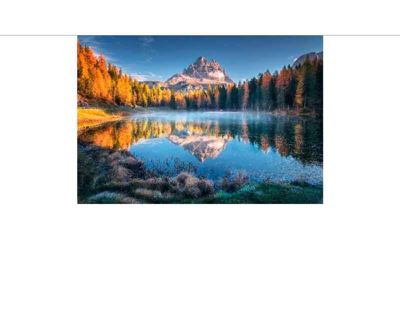 Sonnenaufgang über einem Berg mit herbstlichen Bäumen, die sich im klaren See spiegeln