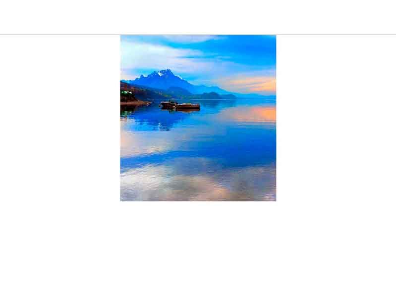 Zwei Boote auf einem ruhigen See mit schneebedeckten Bergen im Hintergrund bei Sonnenuntergang.