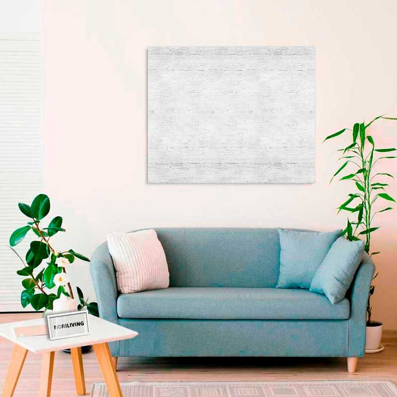 Ein modernes Wohnzimmer mit blauer Couch, Kissen, einem niedrigen Tisch und Pflanzen. An der Wand hängt ein minimalistisches Bild.