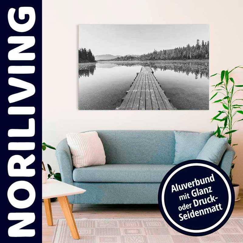 Helles Wohnzimmer mit blauer Couch, Holzfußboden, Pflanzen und einem Wandbild, das einen Steg über einen ruhigen See zeigt.