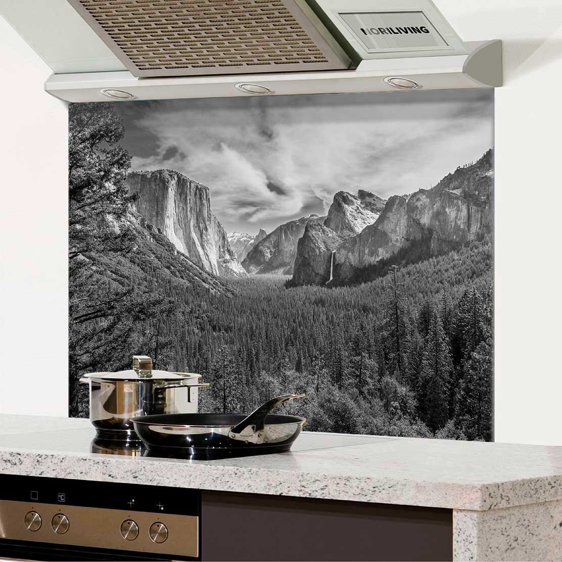 Küchenrückwand zeigt ein Schwarz-Weiß-Fotografie einer beeindruckenden Berglandschaft mit Bäumen und Wolken.