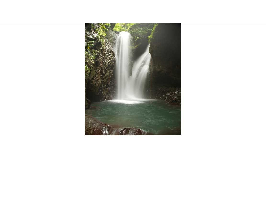 Ein beeindruckender Wasserfall fällt in einen smaragdgrünen Pool, umgeben von üppiger Vegetation und Felsen.